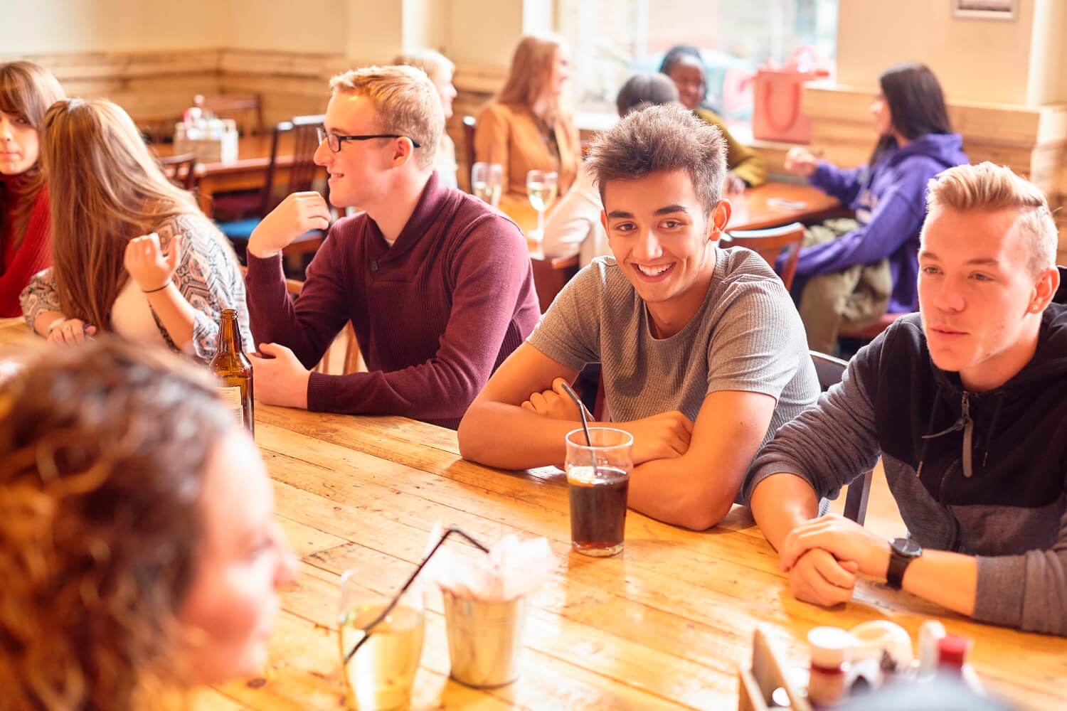 Students chat while sat around a table in the SU Bar.