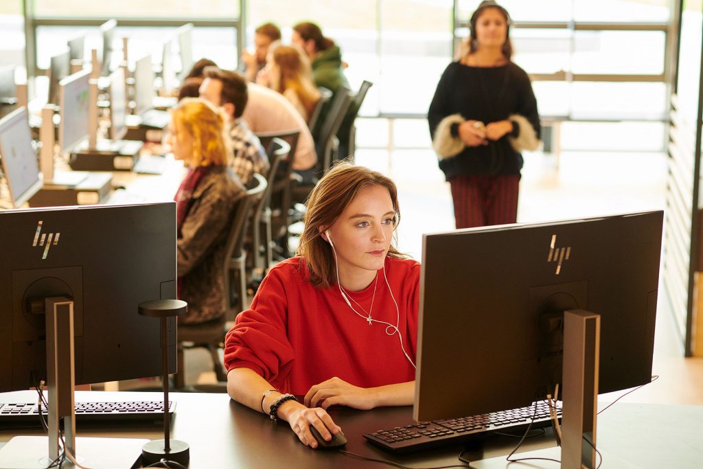 Student sat at desktop computer screen with neutral expression