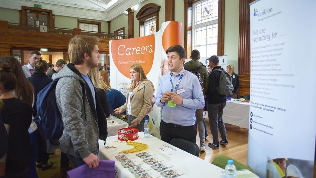 In this image there is a careers fair taking place on the Edge Hill University campus. This image focuses on one student talking to an employer.