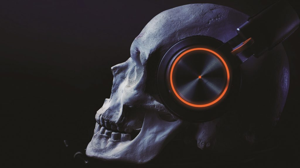 Human skull with blue-tooth headset with led highlight laying on a table on black background.