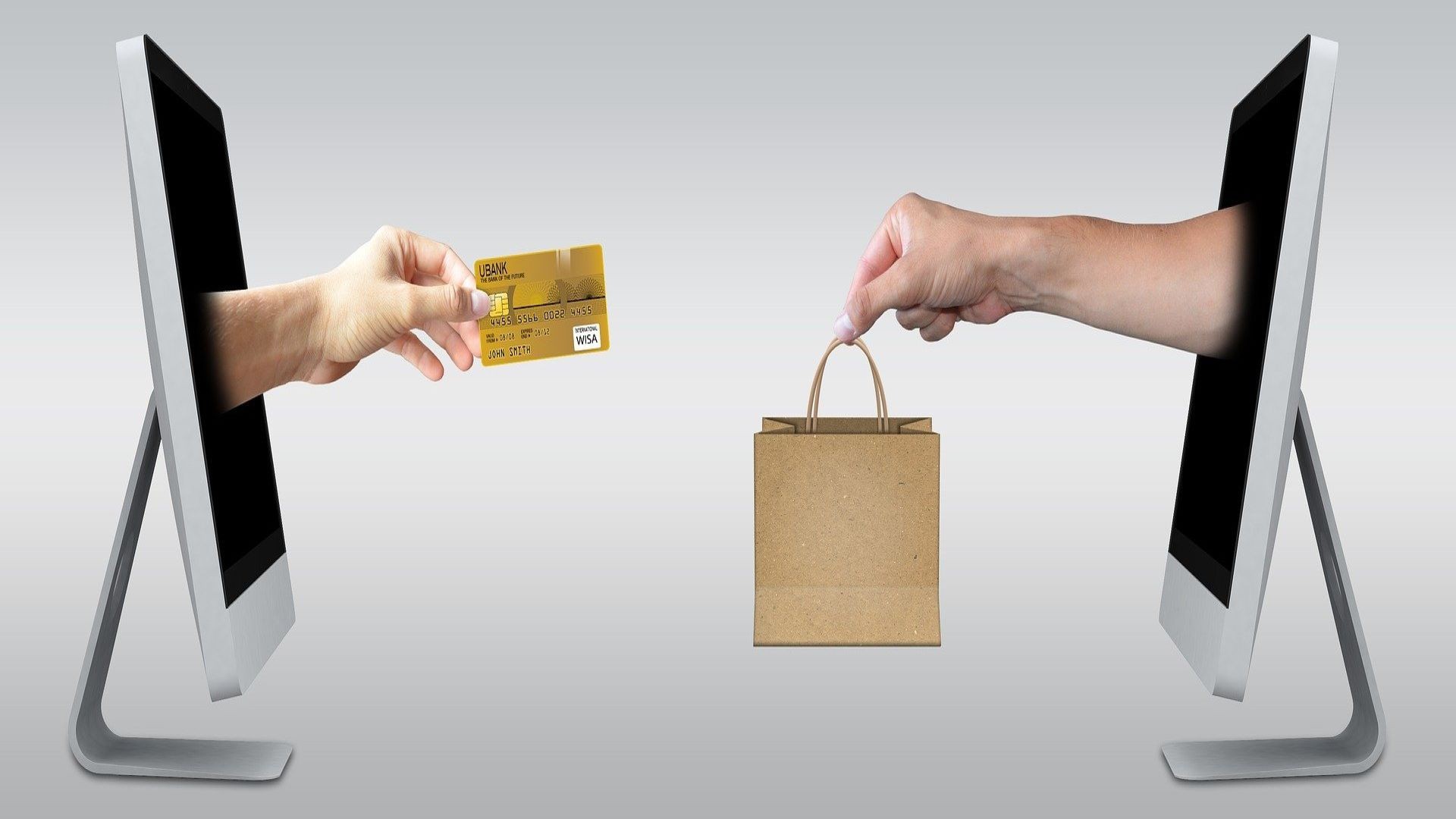 Two monitors facing each other with a hand coming out of each of them, one holding a bag and the other holding a bank card.