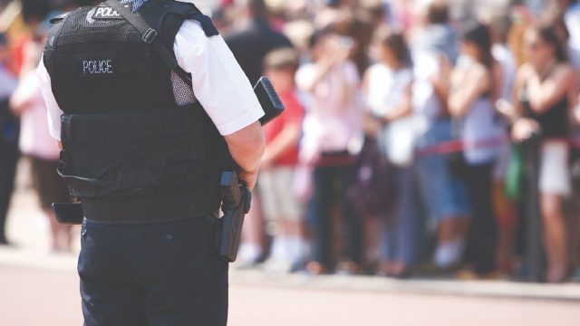 An image of a police officer stood in front of a crowd.