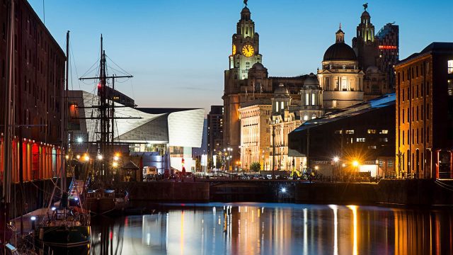 An image of the waterfront at night in Liverpool city centre, there are various well-lit buildings.
