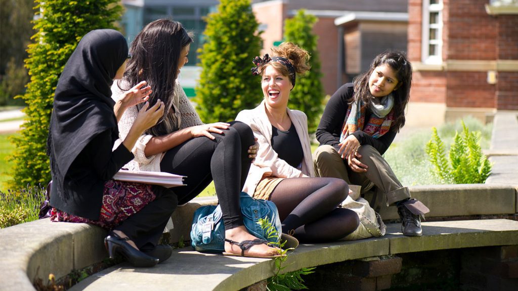 A group of student sit outside laughing with each other