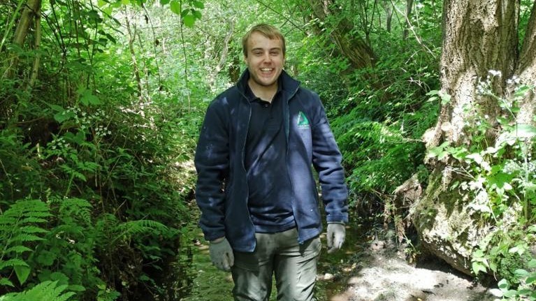 Student standing in forest
