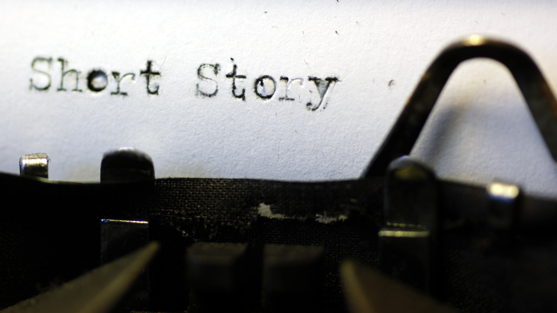 A close up of a type writer with a white sheet of paper including the typed words 'Short Story'.