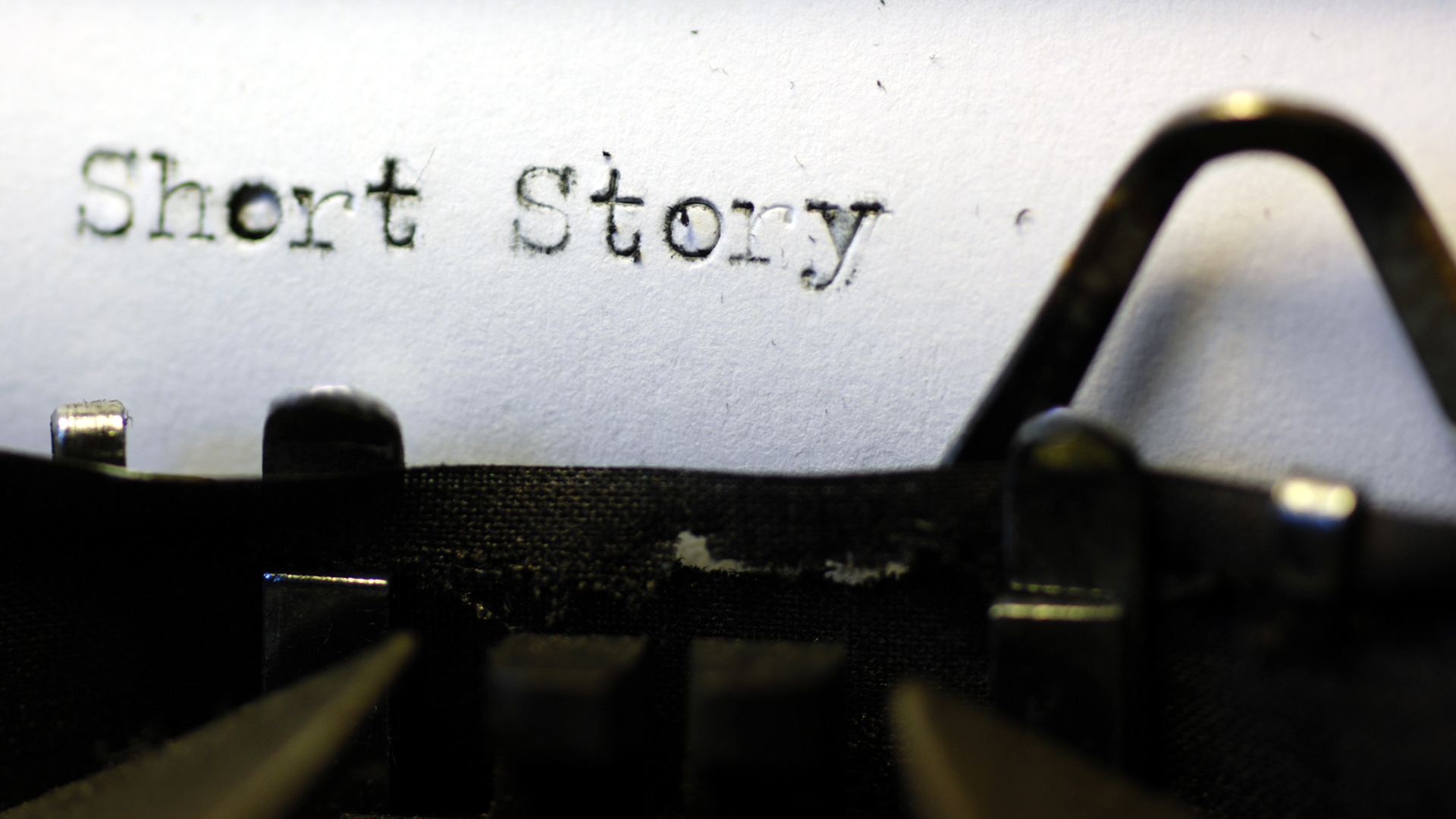 A close up of a type writer with a white sheet of paper including the typed words 'Short Story'. Edge Hill Short Story Prize 2023.