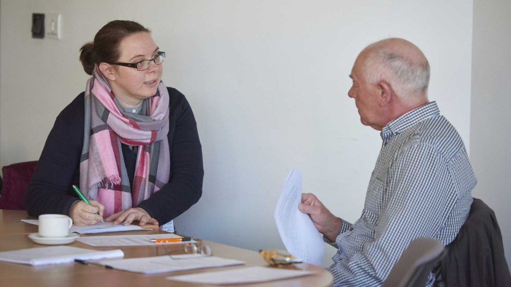 Social worker talking to a man sitting at a table