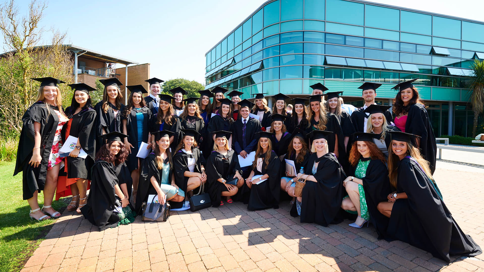 A large group of graduates celebrate their success on campus.