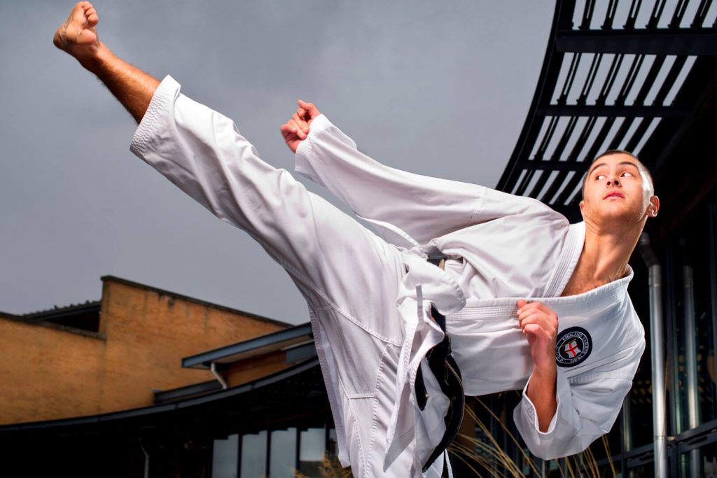 A former Sports Scholarship winner in ju-jitsu pose and outfit outside Wilson Centre.