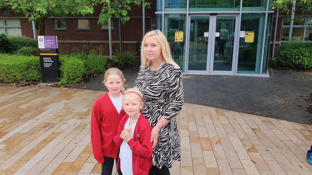 Kerry Smith with her daughters standing in front of the Education Piazza building