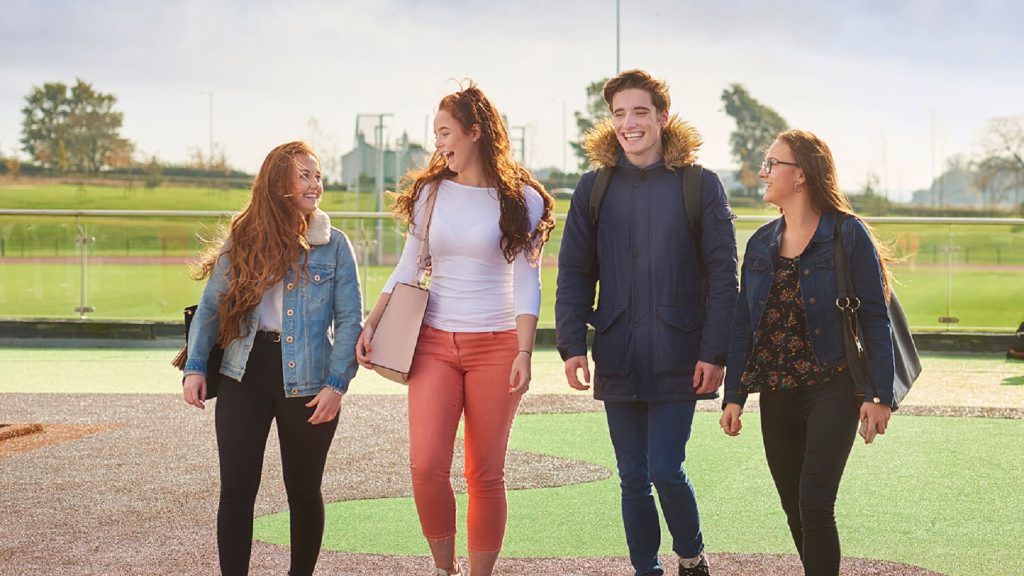 An image of four people walking through the outside sports area on the Edge Hill University campus
