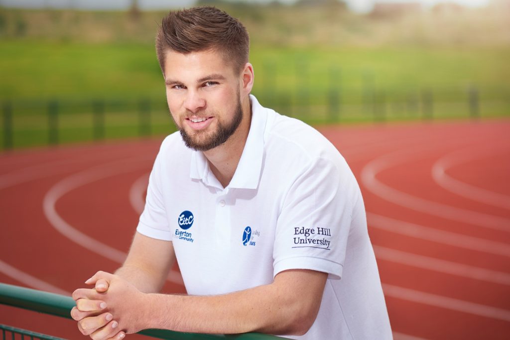 Sports Scholar Michael Lowe standing by the running track adjacent to the Sports Centre on campus.