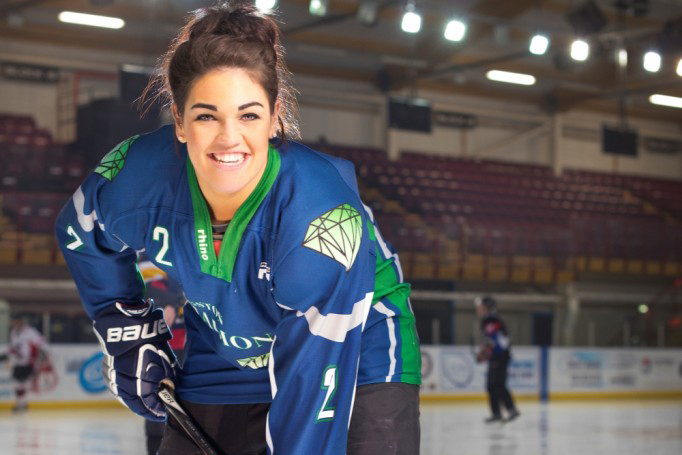 Sports Scholarship winner Sarah Hutchinson on ice rink, wearing her hockey kit, and holding a puck.
