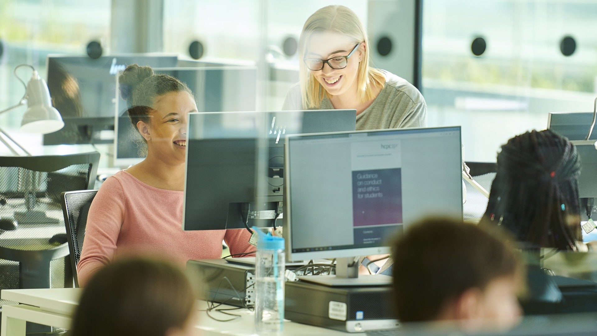 2 people are looking at a computer screen.