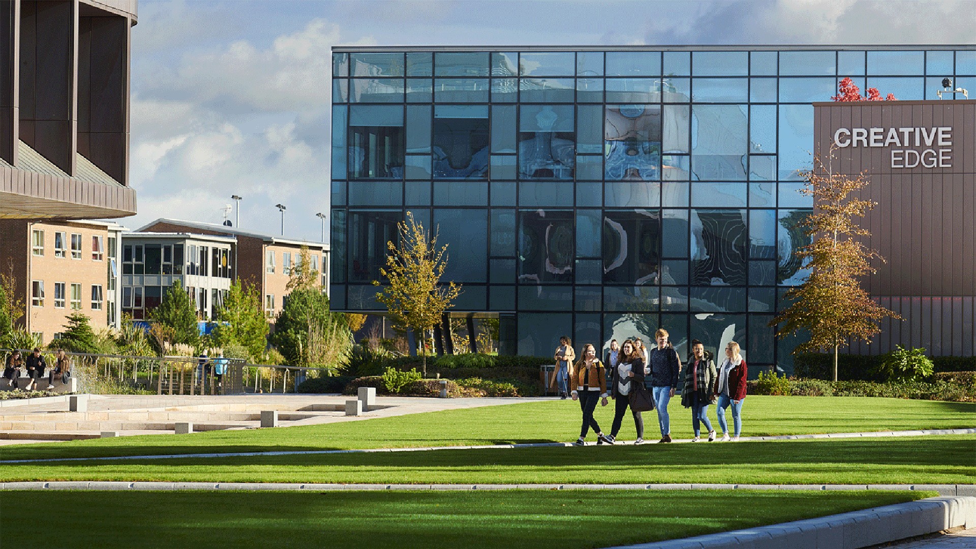 An image of people walking across the Edge Hill campus away from the Creative Edge building