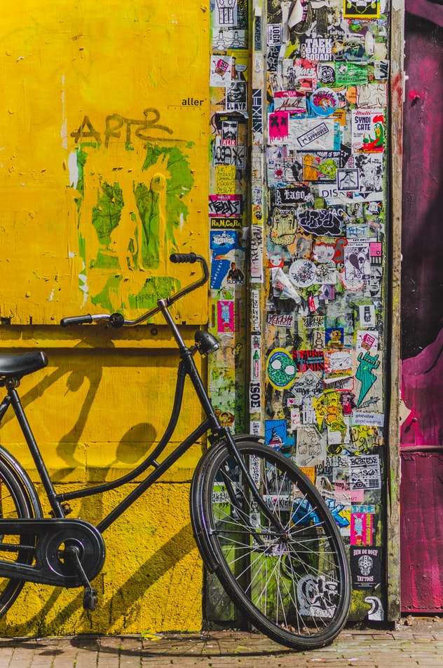 A yellow wall with vibrant graffiti. A bike can be seen leaning against it.