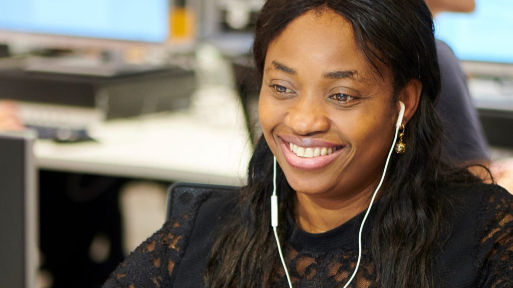 An image of a person smiling at something on a computer.