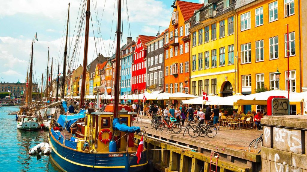 Canal in Copenhagan with boats and people eating at cafes