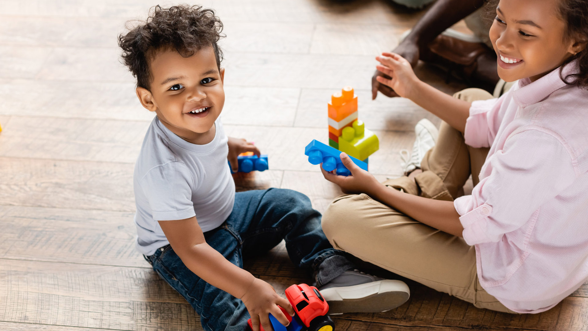 Two happy children playing with toys on the floor