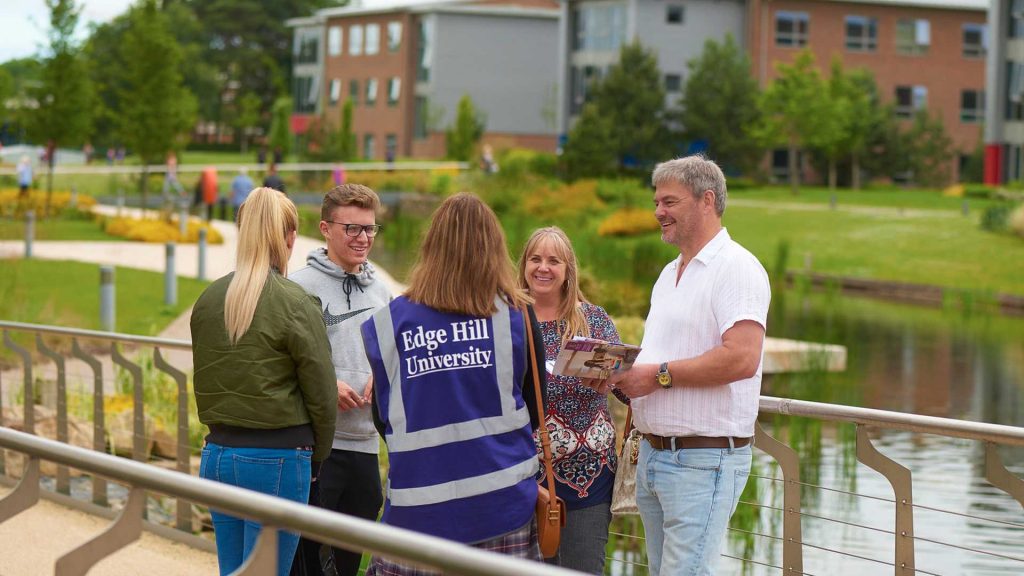 An EHU member of staff in a purple bib shows a student and their parents around campus on an offer holder day