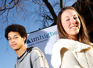Two students pose for photo by Aimhigher signage