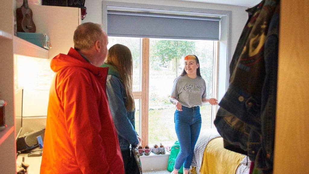 An image of three people stood inside an on-campus accomodation room. 