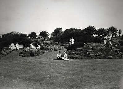 An old photo of the rock garden, with two students sat on the grass