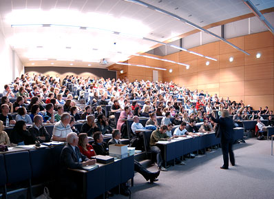 A lecturer addresses a room full of staff in a lecture theatre