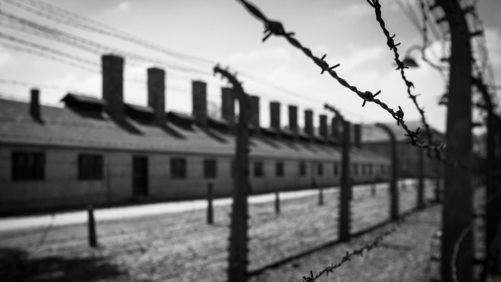 A black and white image of the gates surrounding auschwitz.