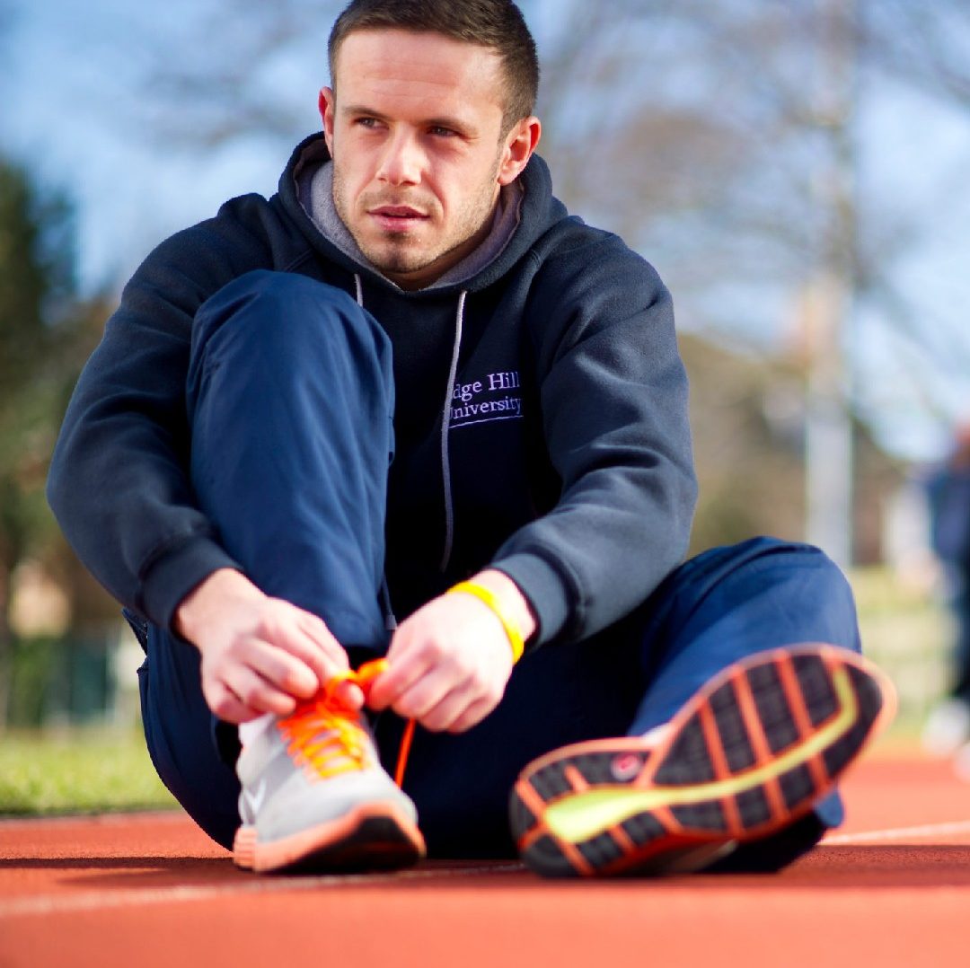 An image of a runner sat on a running track.