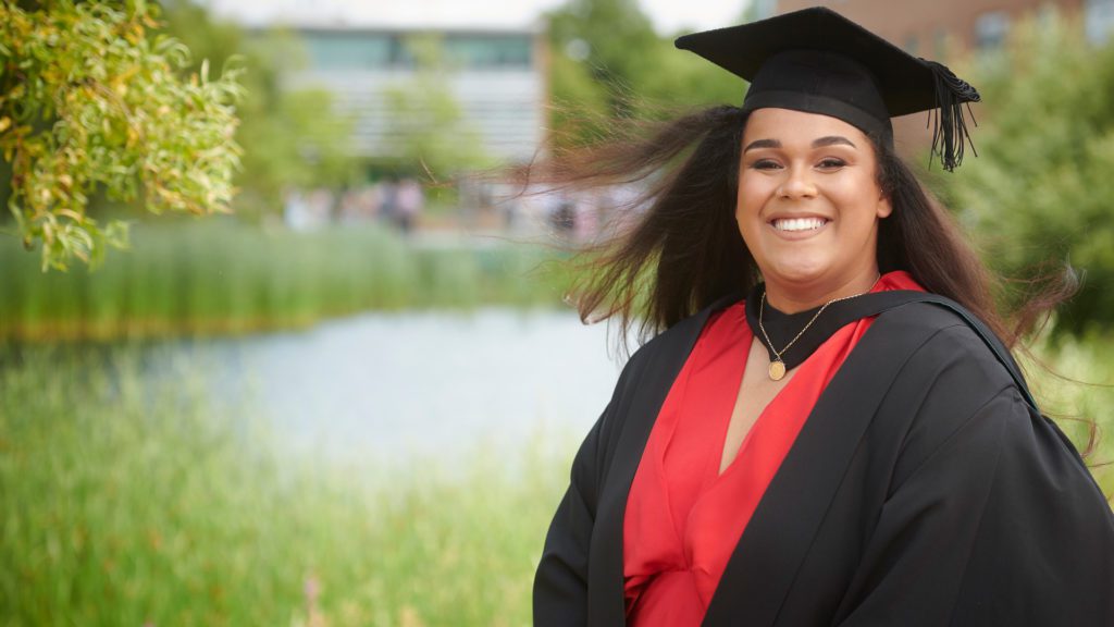 Ellesha Steadman wearing a red dress and a graduation cap and gown