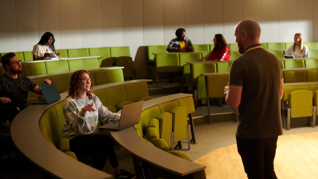 A student talks to a tutor during a lecture.