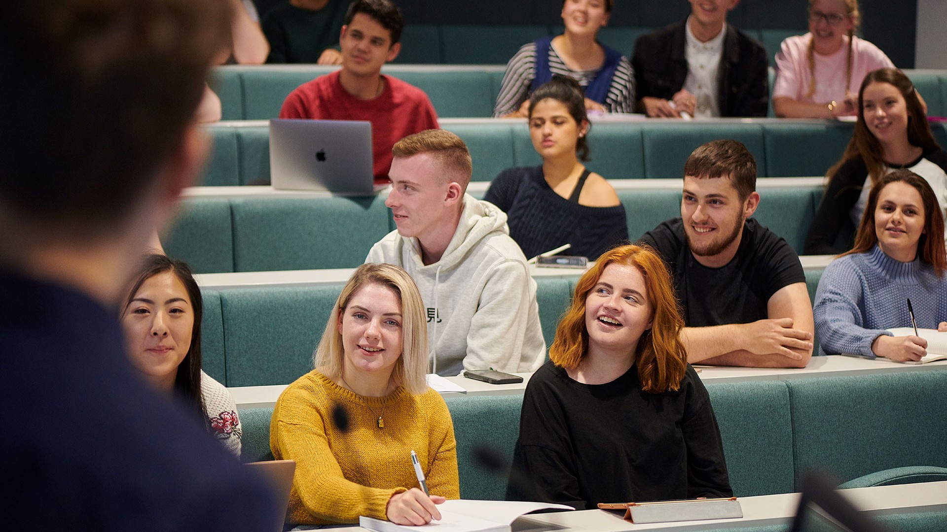 A group of students are attending a lecture in a lecture theatre.