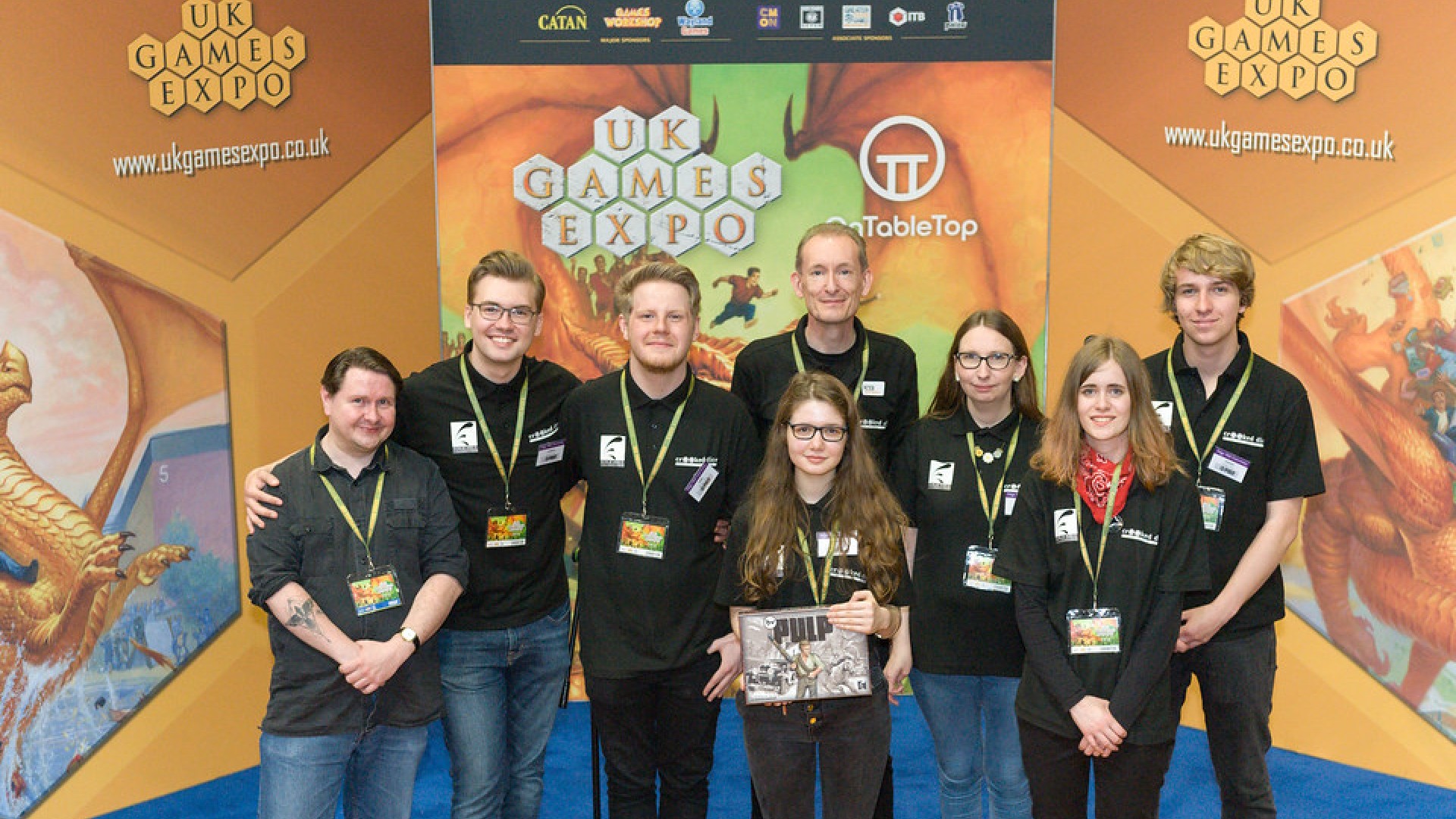 An image of a group of Edge Hill students and Dr Peter Wright stood in front of a sign that says "Uk Games Expo".
