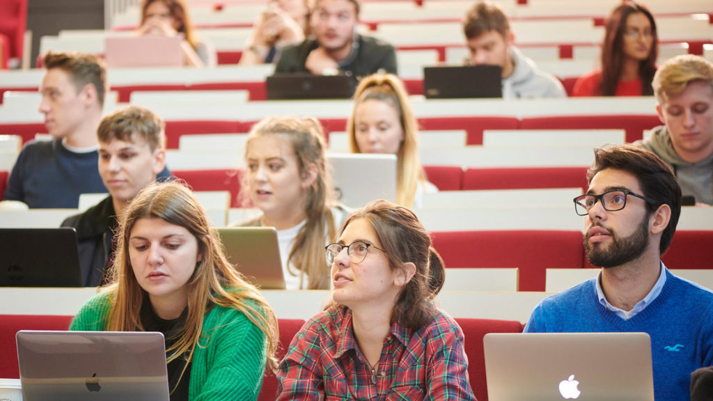 rows of students in a lecture hall with red seats