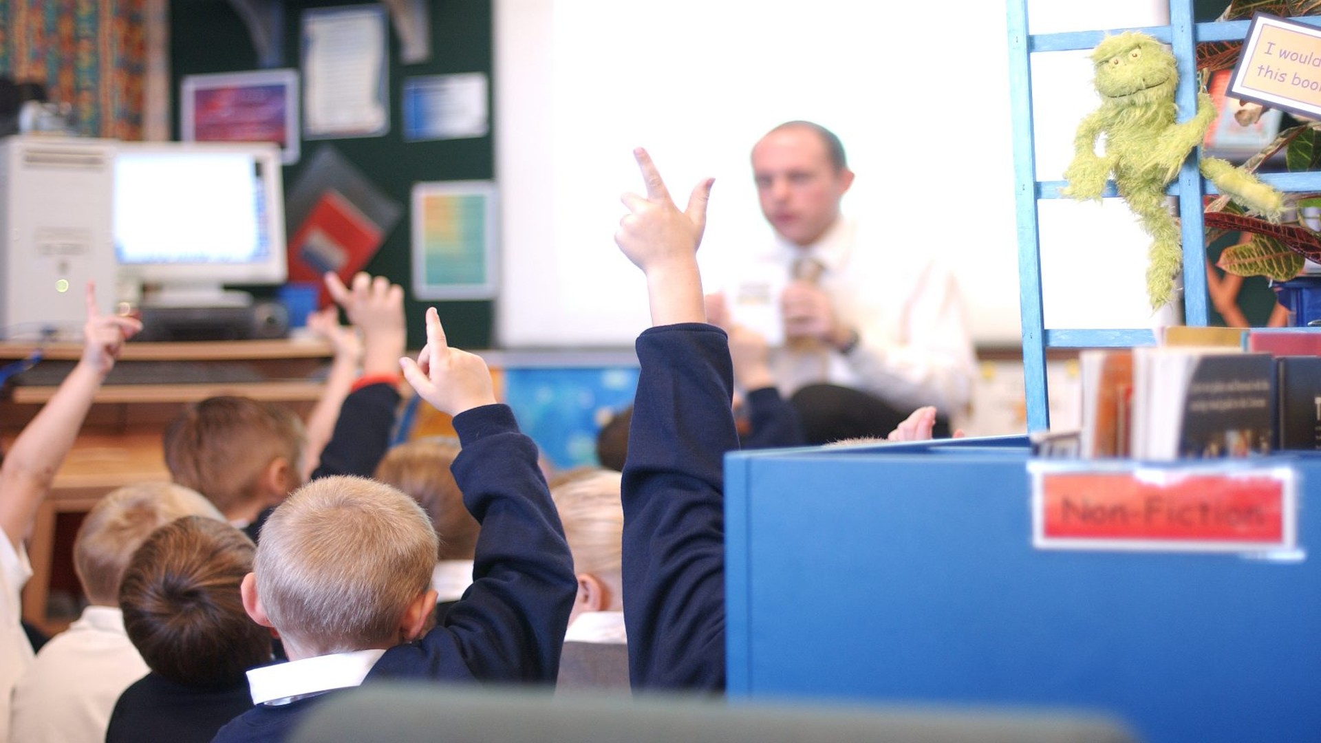 A classroom of children with their hands up