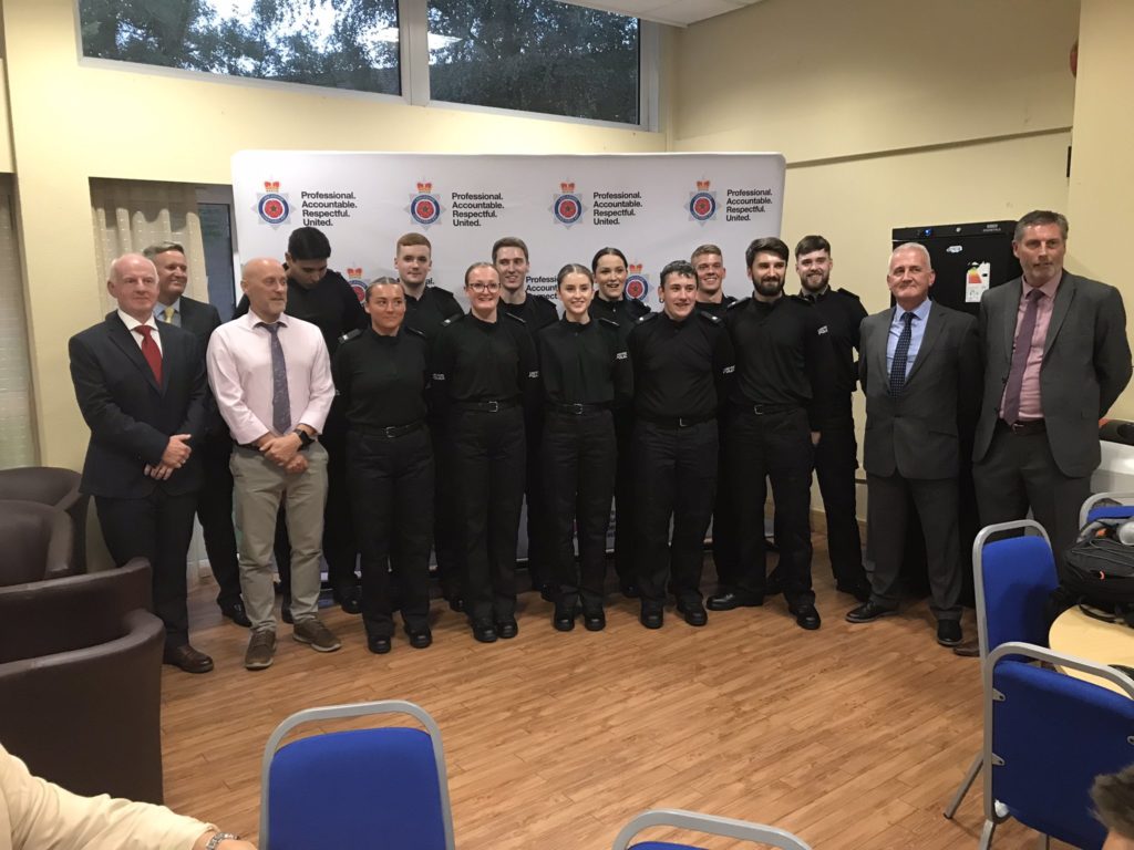 A picture of Edge Hill Policing students in a police uniform with their proud lecturers.