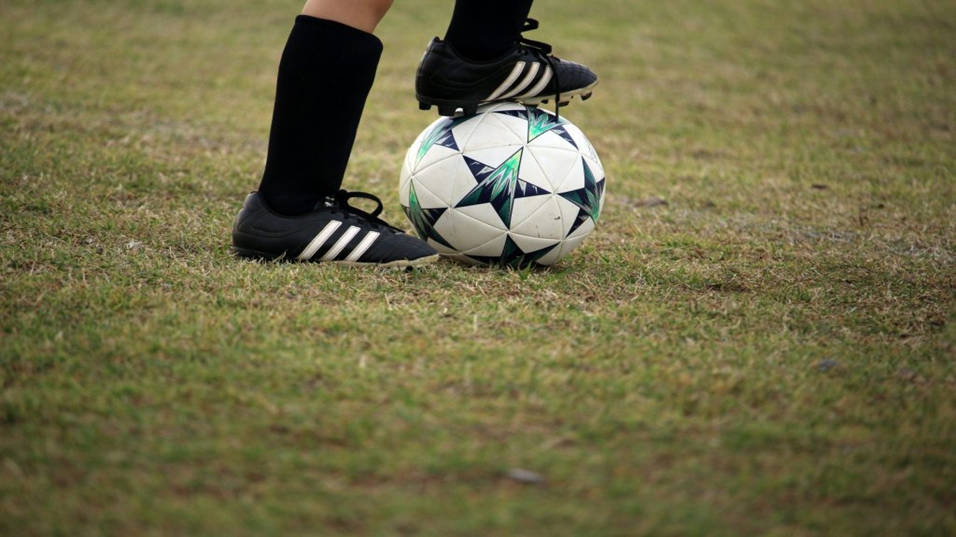 A picture of a football player with one foot on the football