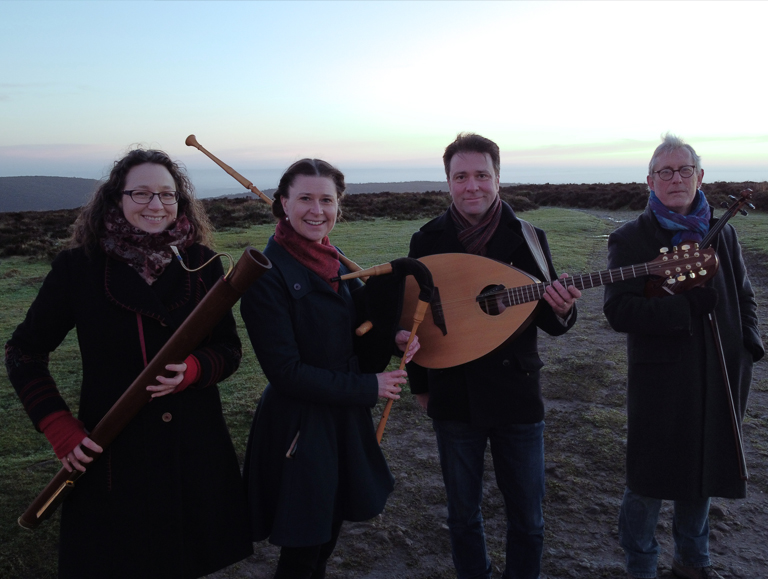Carol group stood with instruments in the countryside.
