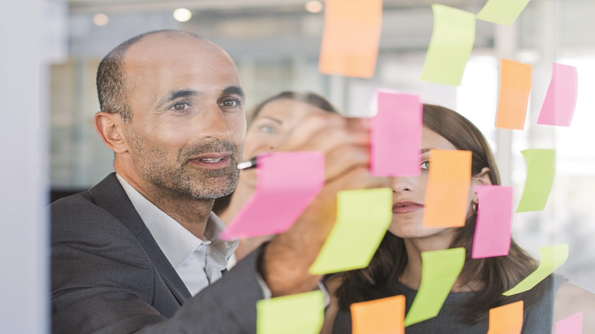 Picture of three people working on post it notes on glass