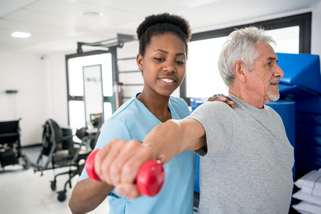 Occupational therapist helping a senior patient with his shoulder workout