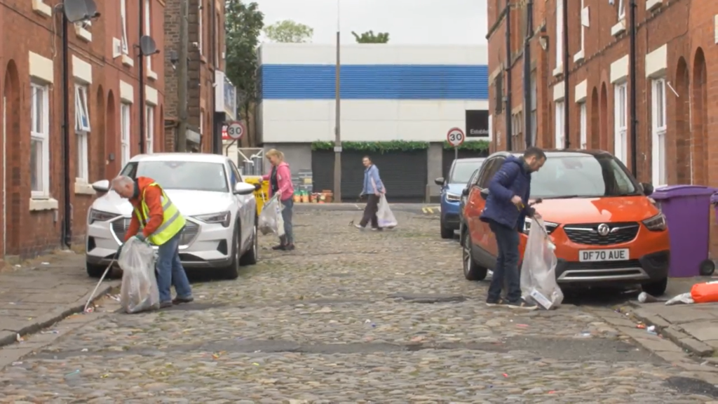 A picture of a group of people litter picking in a street. 