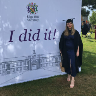 Chrissie Byrne at graduation in front of a banner