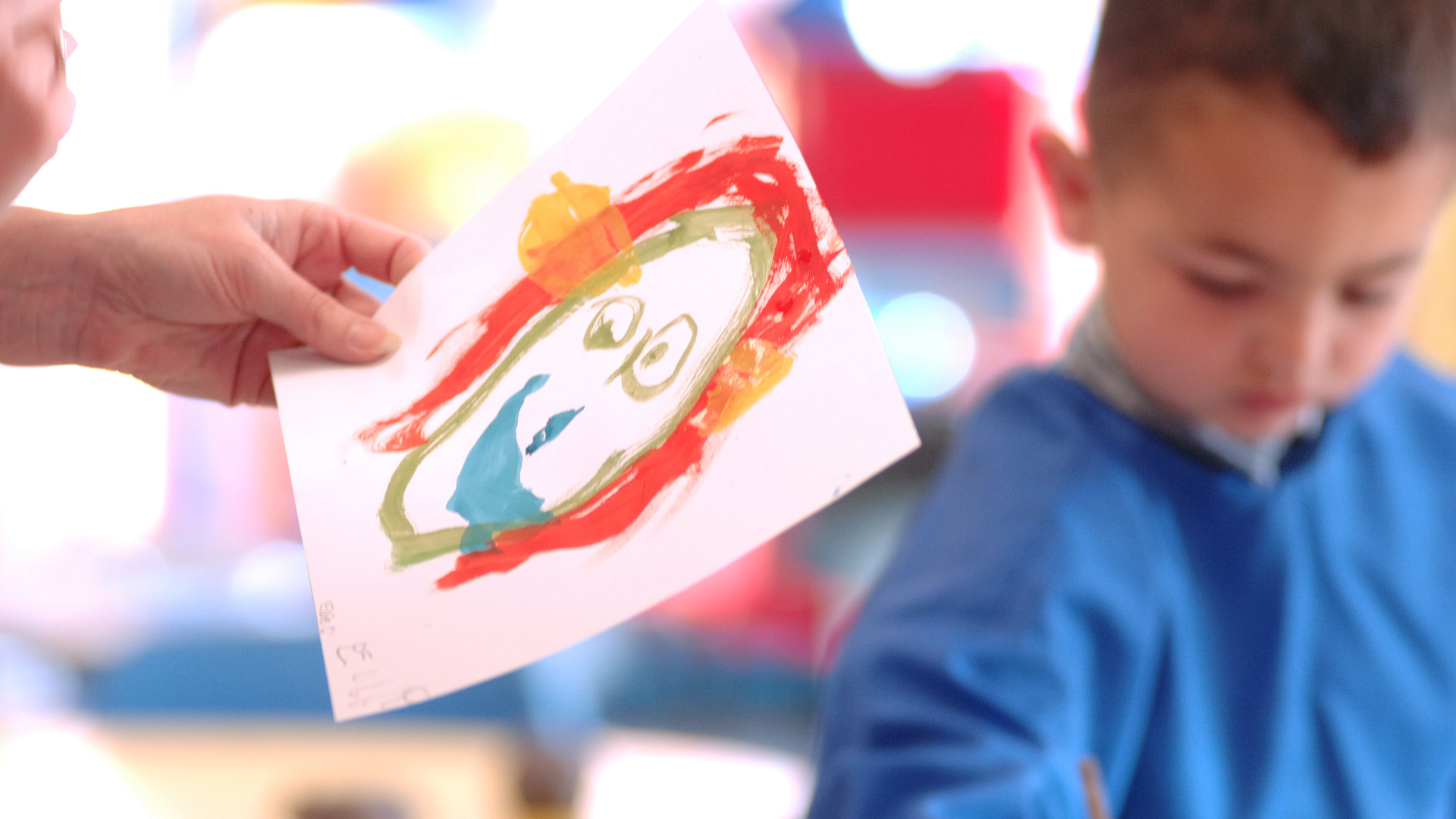 A colourful childs painting and a blurred child in the background