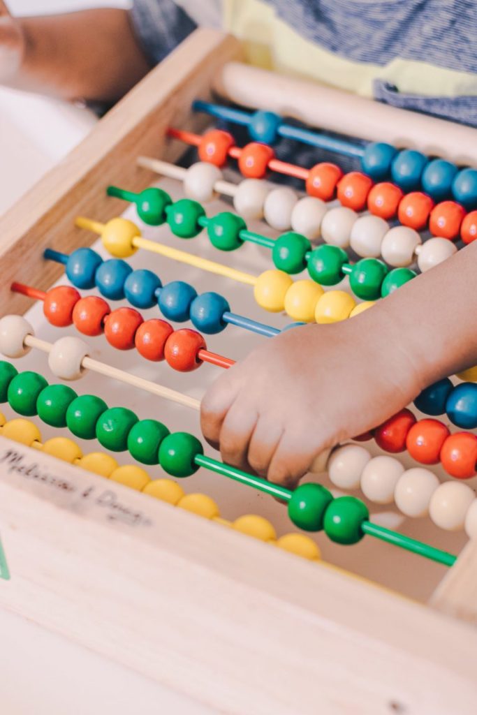 A picture of a child's hand playing with an abacus