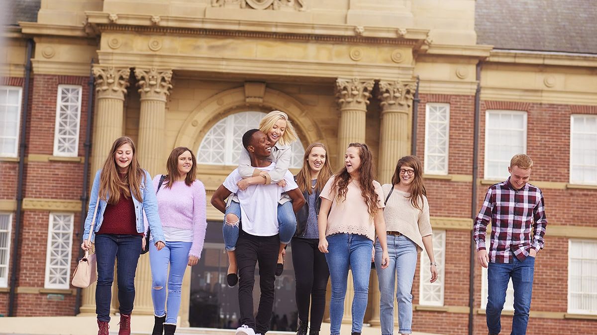A group of students walk away from the main building entrance