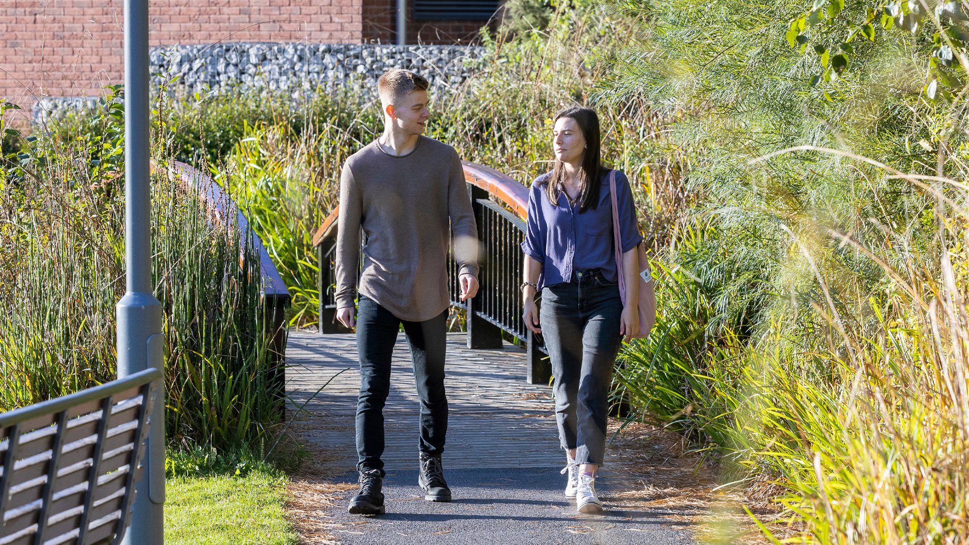 Two students walking across a bridge on campus