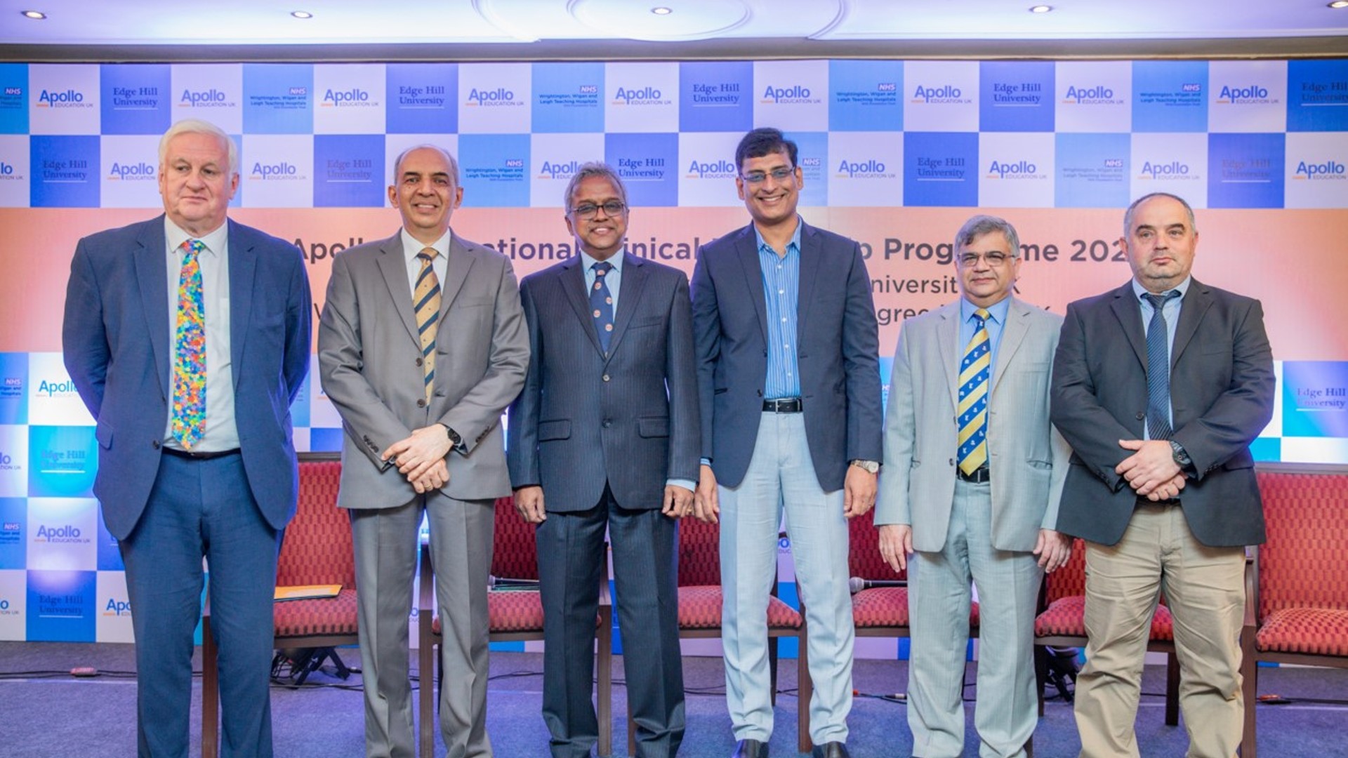 Six health professionals stand in a line smiling at the camera.