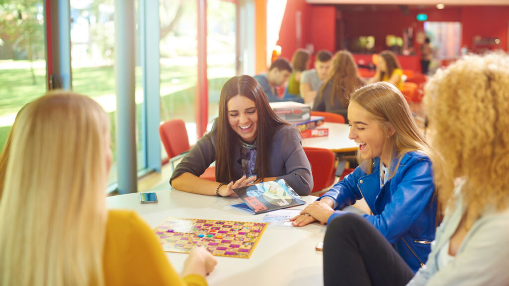 Four students are playing board games together at the Arts Centre.